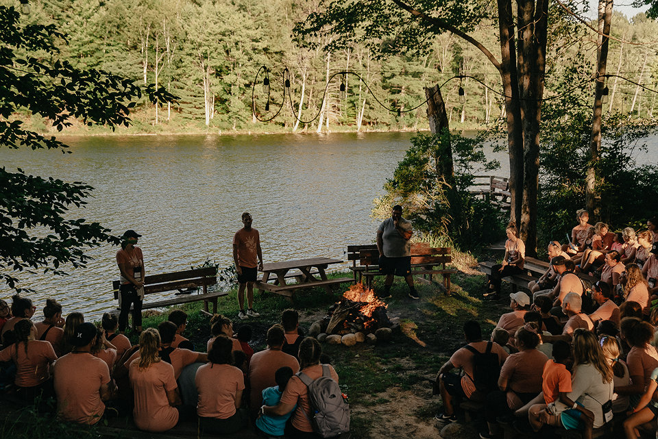lfac campers gathered around campfire by the lake listening to camp leaders share stories