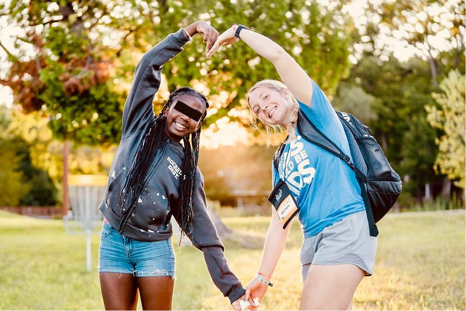 lfac two campers forming heart shape with arms in field at sunset showing friendship and joy
