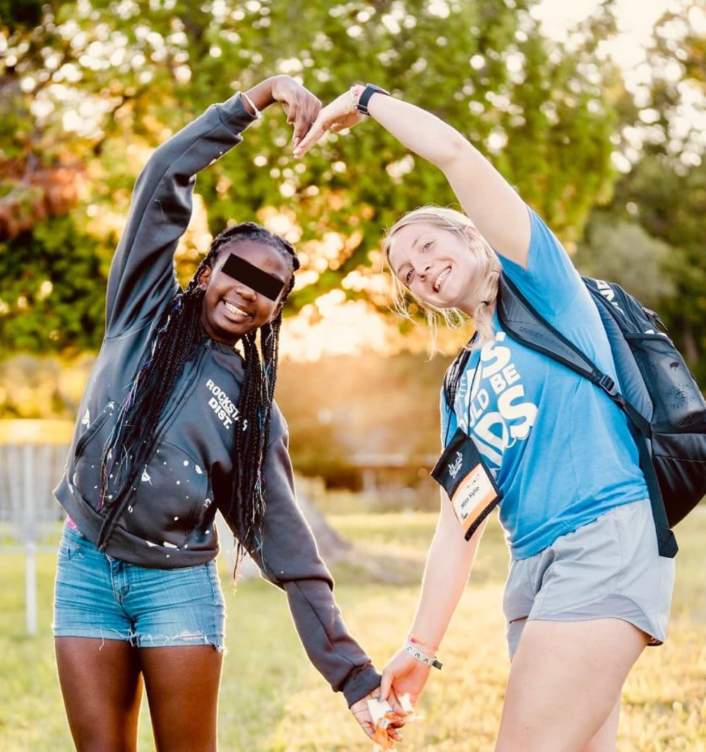 lfac two campers forming heart shape with arms in field at sunset showing friendship and joy